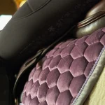 Purple quilted horse saddle pad positioned under a black saddle in a stable setting